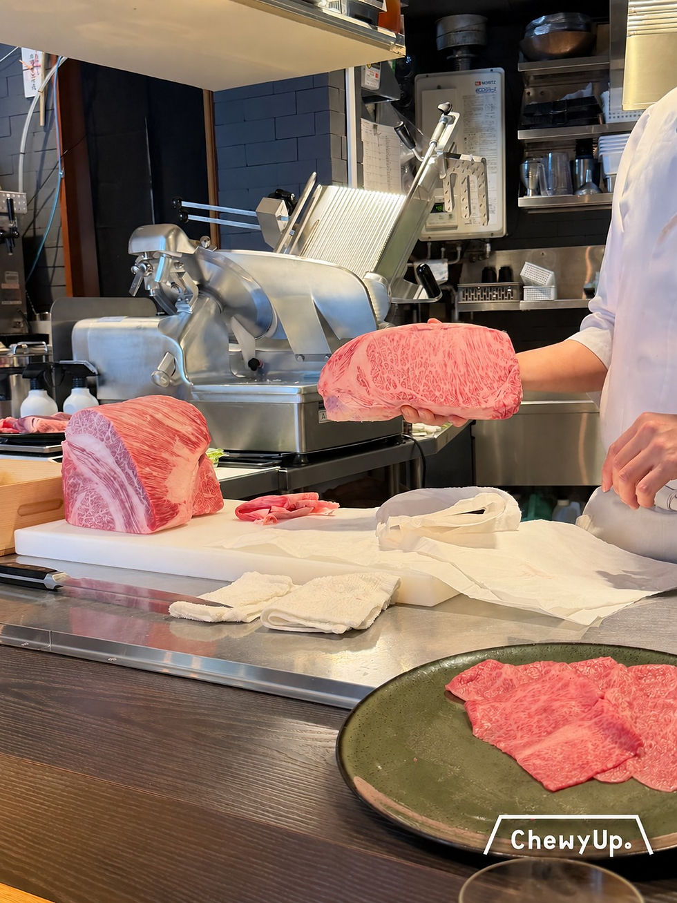 廣尾すき焼き十二天的吧檯工作台,店員展示即將切片的霜降牛肉。