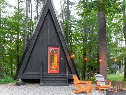 A-frame cabin in the woods with string lights and outdoor seating, representing a short-term rental property financed with a DSCR loan.