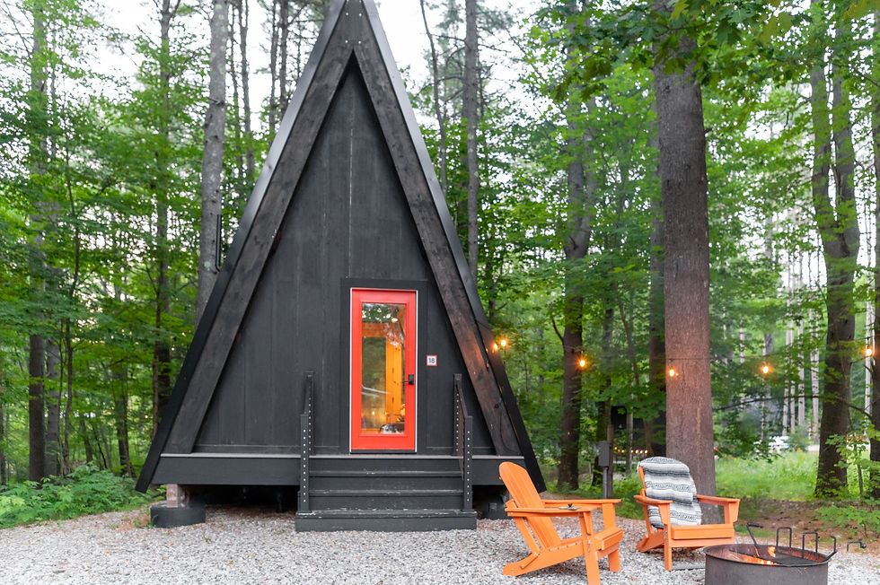 A-frame cabin in the woods with string lights and outdoor seating, representing a short-term rental property financed with a DSCR loan.