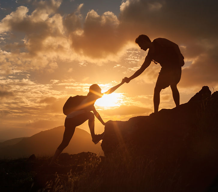 Male and female hikers climbing up mountain cliff and one of them giving helping hand. Pe