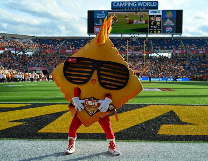 Cheez-It mascot with sunglasses posing on the field at a stadium.