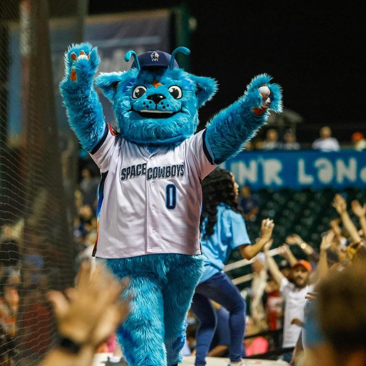 Blue furry mascot with the words "Space Cowboys" on its shirt, raising its arms in excitement