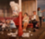 A colorful vintage photograph depicting a red bench and those around it. An older couple sits on the right side of the bench, snacking. To the left side, a young child in a stroller is visible in frame, crying.