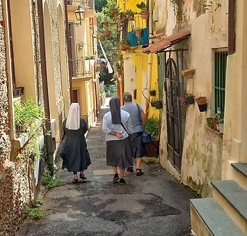 Suore camminano in un vicolo stretto e antico.