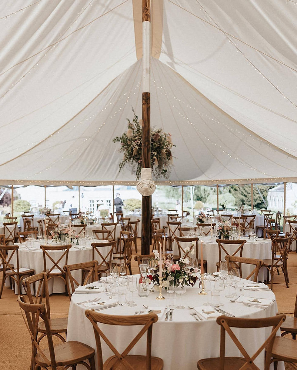 Small round tables inside a Peacock and Bow pole and canvas marquee.