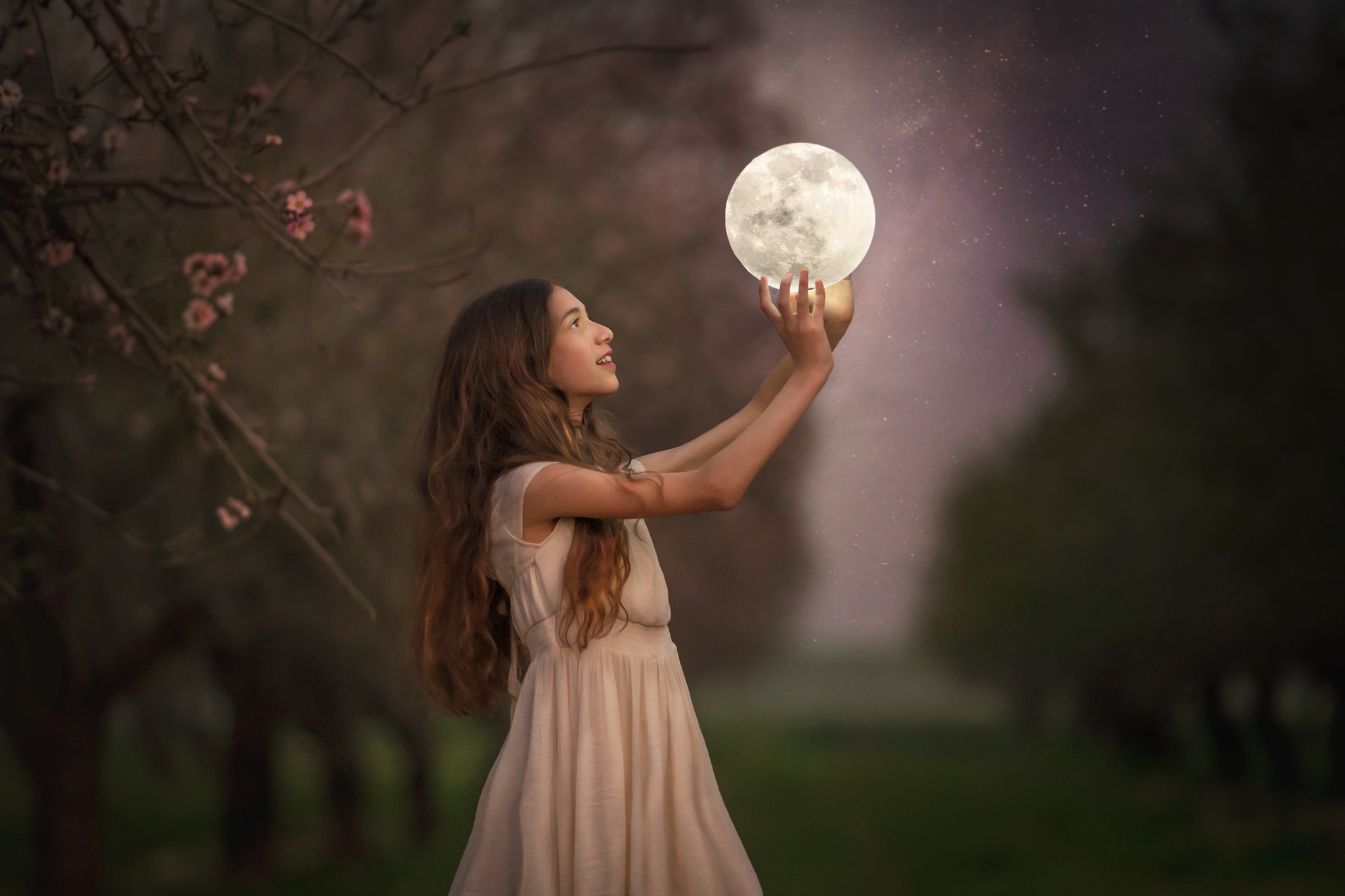 דוגמה לתמונה מבוק בת מצווה. להגדלה לחצו עליה. נערה מחזיקה בתוך מטעי שקדיות ירח על רקע שמיים