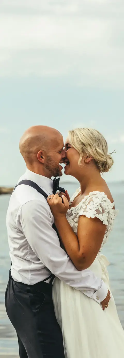 Brudepar i ekstase på en strand, smilende stemning.