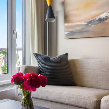 Stilren sofa med røde blomster på bordet.