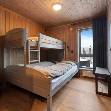 Soverom med køyeseng og trepanel.