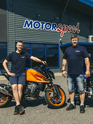 To selgere fra Motorspeed poserer med en KTM foran butikken.