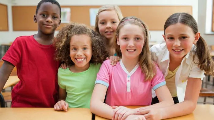 An image of smiling children in a classroom, illustrating equity and access in school education by promoting fair opportunities and inclusive practices for a supportive learning environment.