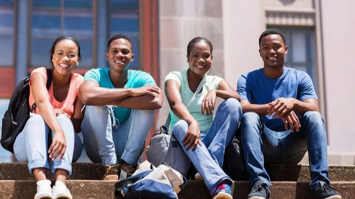 An image of Black and Brown students sitting on campus steps.