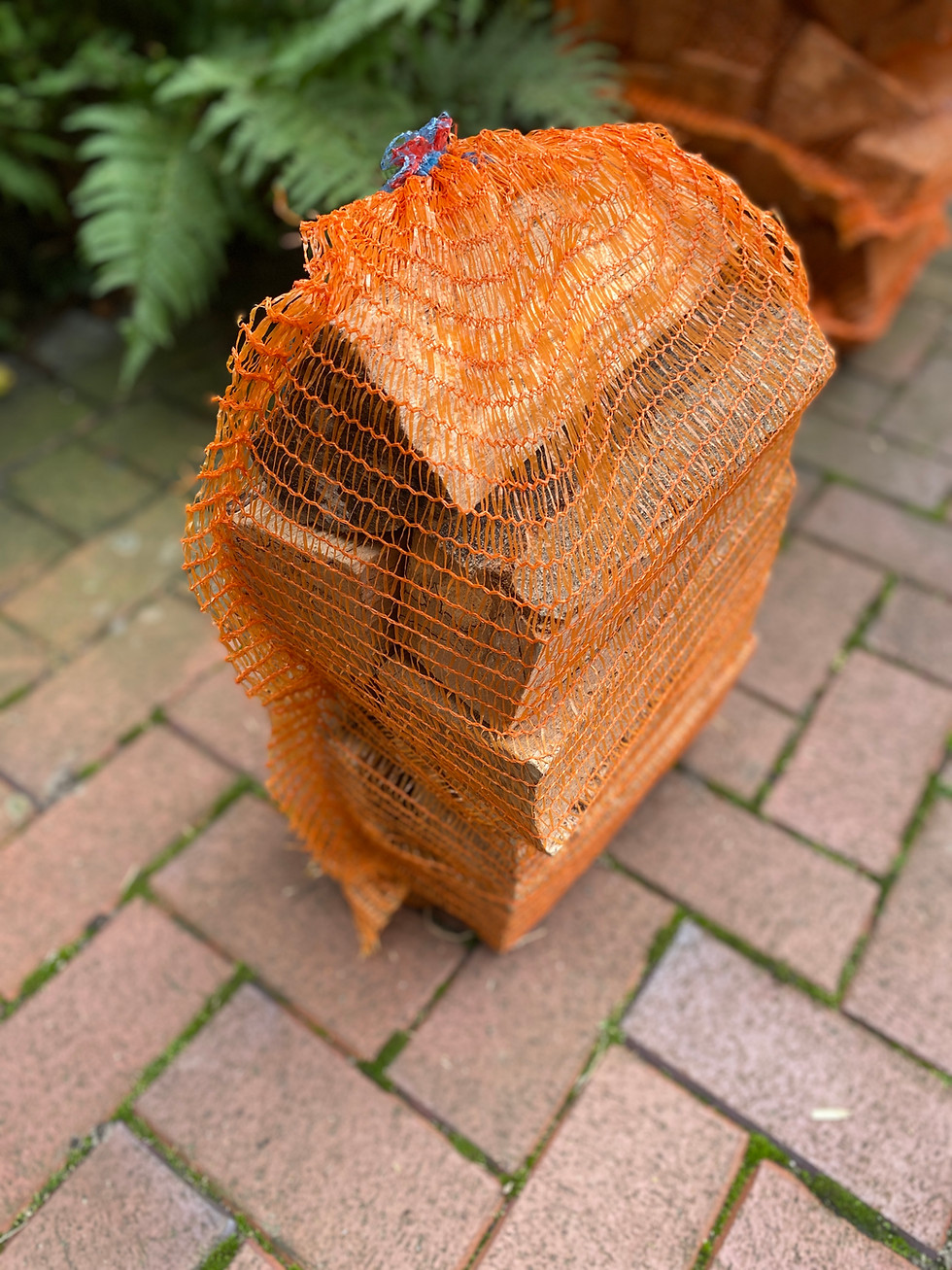 Holzscheite in orangefarbenem Netz. Holzscheite für Kamin oder Ofen. Eichenbohle sind sichtbar.