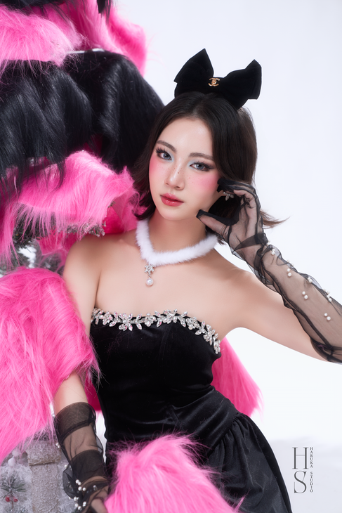 a woman in a black dress with a white necklace and black gloves