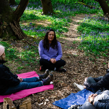 Julie Willis leads an outdoor group session in a serene forest.