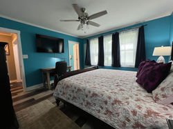 Large work desk in master bedroom with rolling chair and desk lamp.