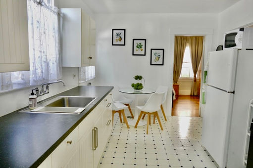 Kitchen with dining table, chairs, refrigerator. The bedroom can be seen from this angle.