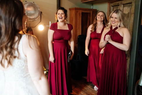 bridesmaids happy reaction to bride in dress