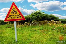 A wooden sign with bold lettering warning passersby to respect fairy lands—or suffer the consequences