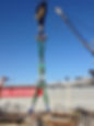A crane holding up a green round sling.