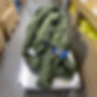 Green round sling being transported on a metal cart.