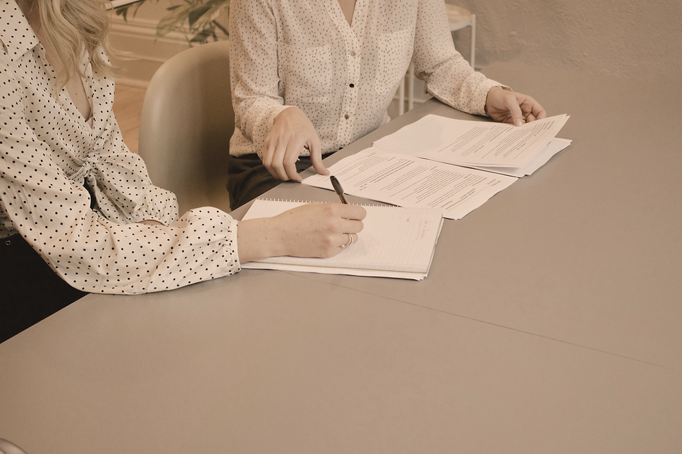 Dos personas revisando y firmando documentos en una mesa