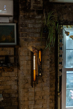 handmade wall lamp on exposed brick next to a window with burnt edges, metal, and stained glass