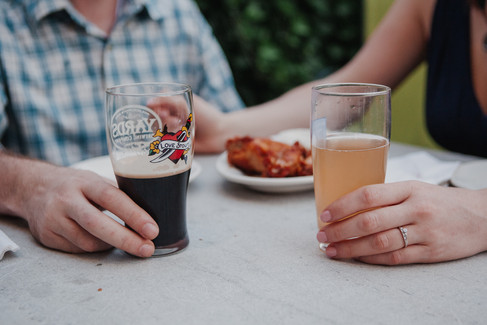 Man and woman on a date at a dive bar with an engagement ring and a yards love stout