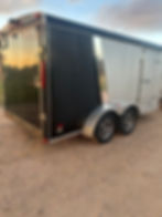 Black and silver enclosed cargo trailers on dirt ground