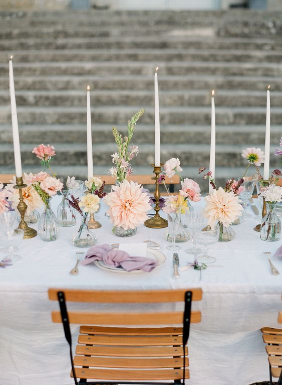 A table set with bud vases and tapered candles