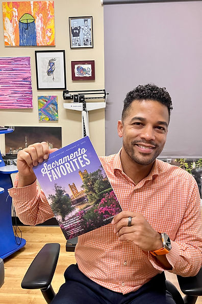 Dr. Rayman smiles while holding the 2023 edition of Sacramento Favorites magazine.