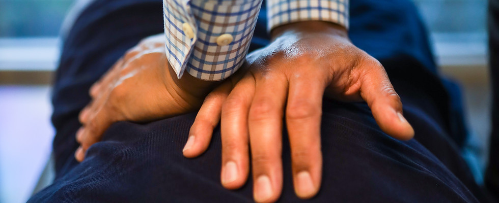 A close up of Dr. Rayman's hands crossed over on a patient's back, getting ready to adjust. 
