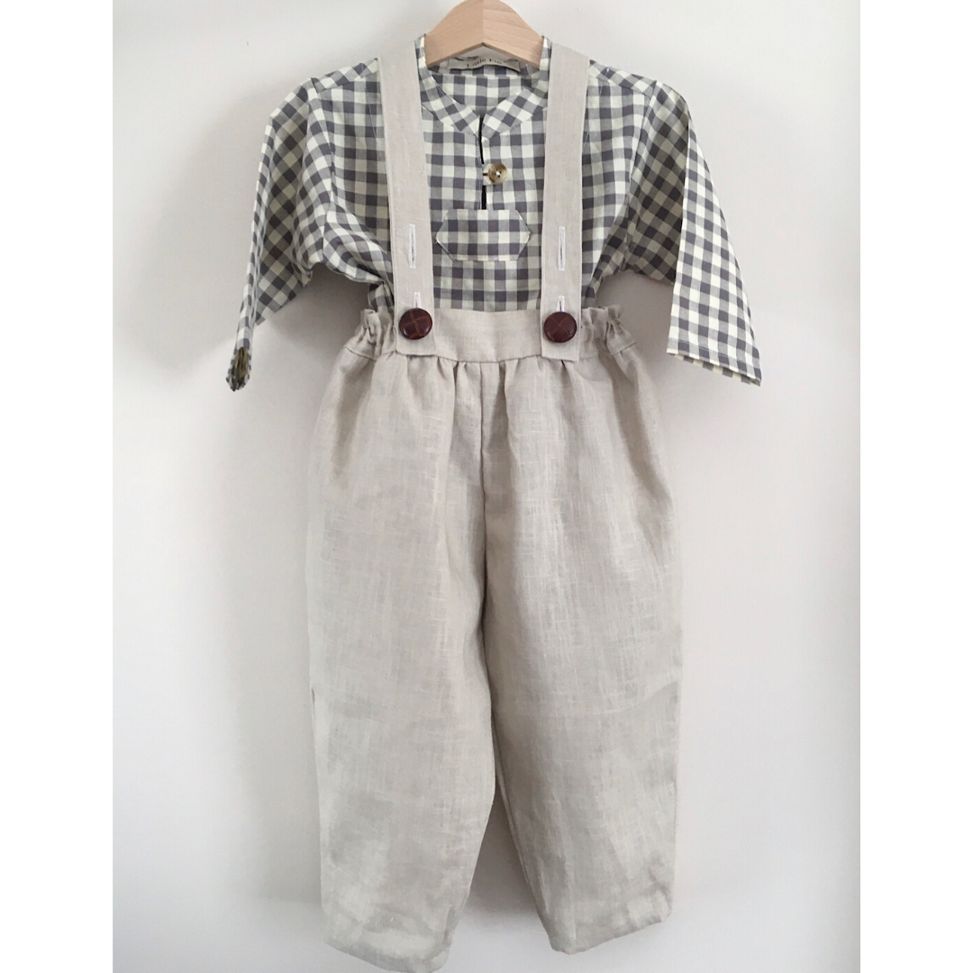 Beige linen baby trousers with brown leather style buttons and a grey check shirt