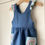 Thumbnail: Side view Navy blue linen children's pinafore dress with crochet frill straps and crochet flower pockets by Little Fig