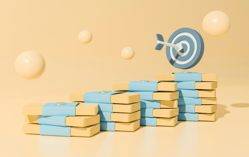 一疊一疊象徵金錢的立體積木往上堆疊,前方有一個箭靶與命中靶心的箭,象徵「金錢目標」與「金錢信念」的調整能讓財務更穩定。