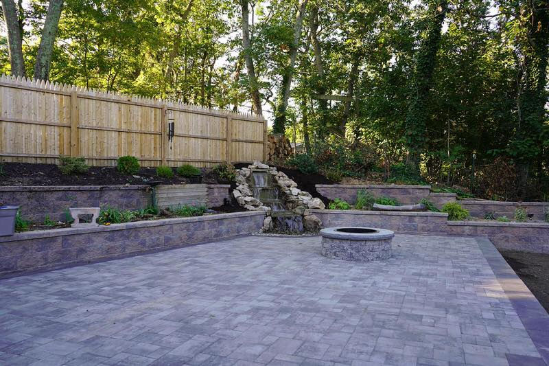 A backyard patio with retaining wall and fire pit.