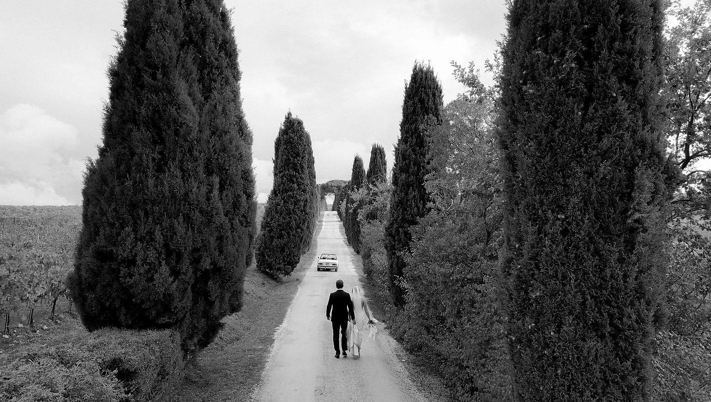 Bride and groom walking through a cypress-lined road during a destination wedding in Italy