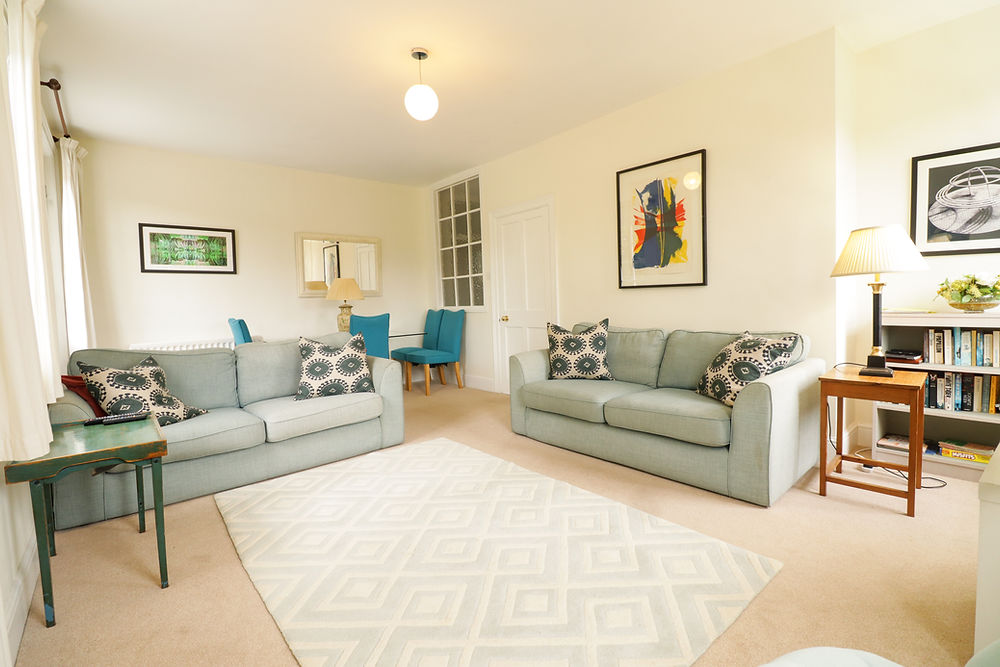 A cream and blue living room, two cosy couches, TV and board games.
