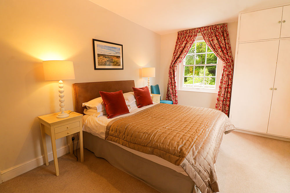 A red and white master bedroom, double bed and natural light