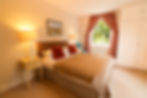 A red and white master bedroom, double bed and natural light