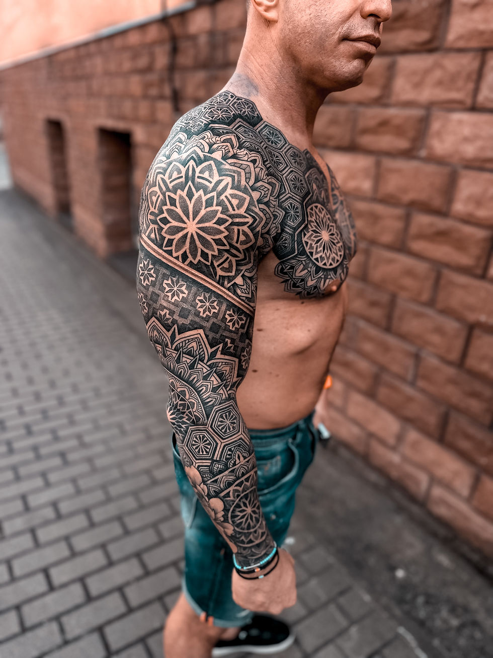 Mężczyzna z geometrycznym tatuażem na całej ręce. Mandale i patterny geometryczne