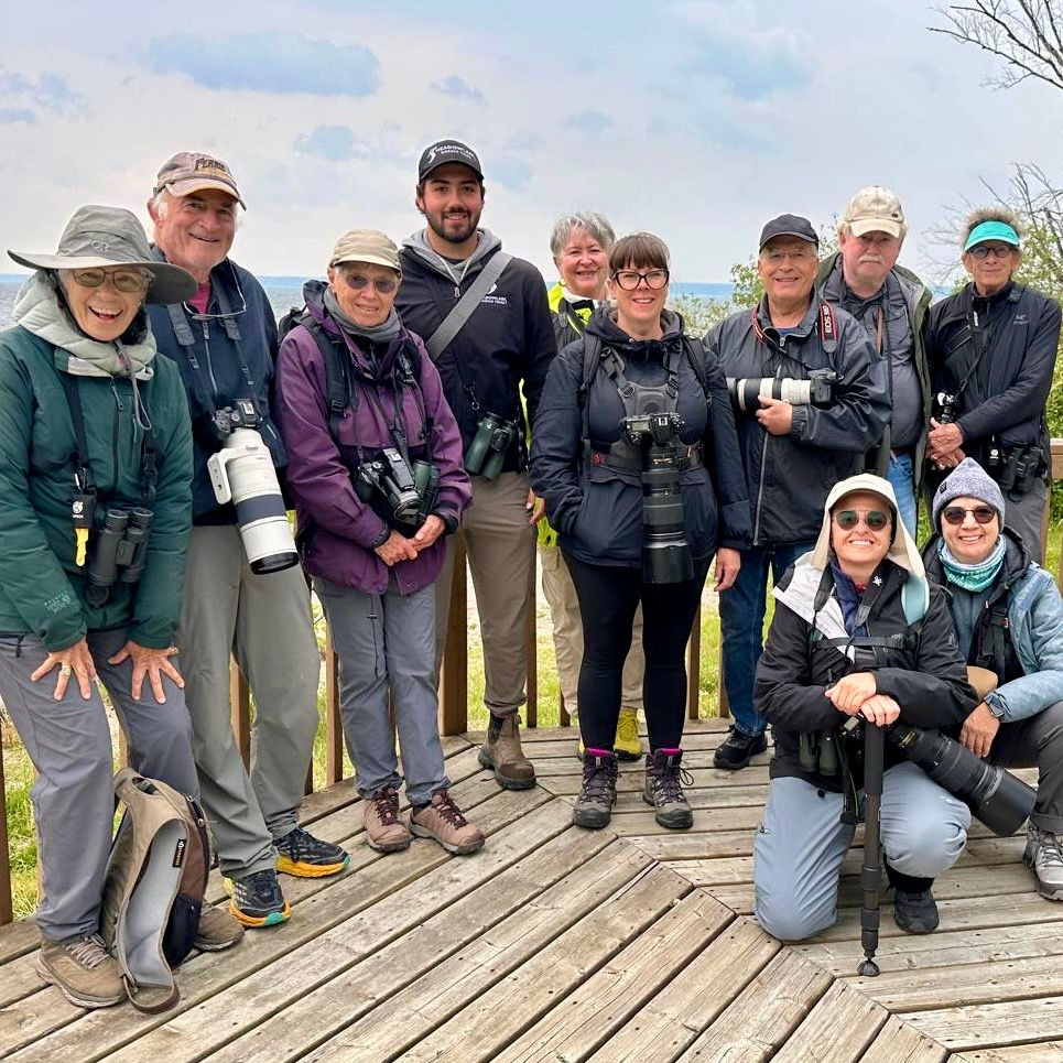 A group of birders on a tour posing on a boardwalk