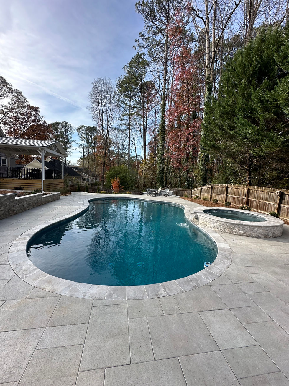 a large swimming pool is surrounded by trees and a fence