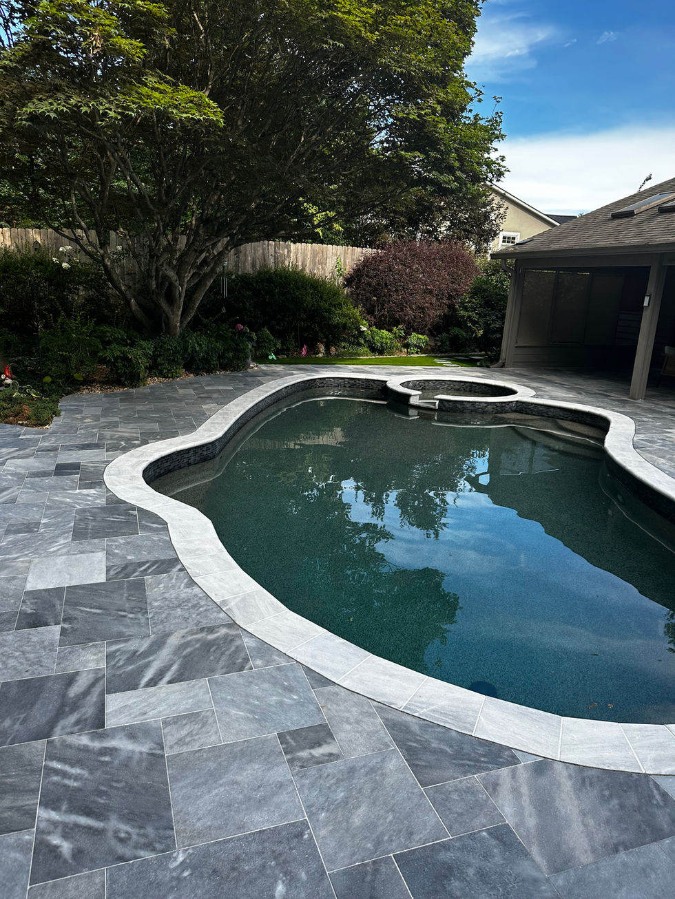 a large swimming pool is surrounded by a tiled patio