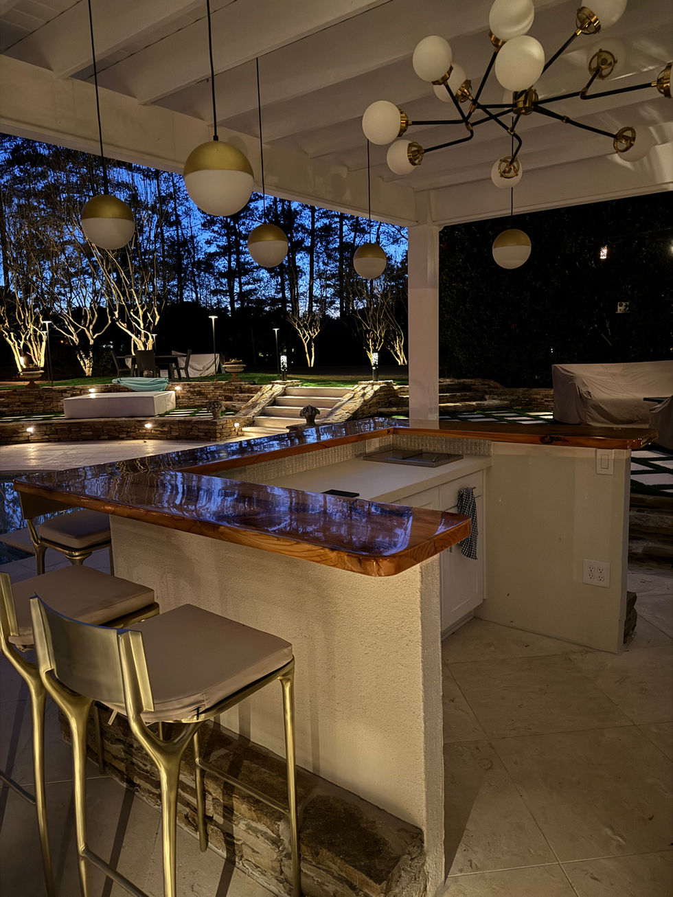 a kitchen with a bar and stools at night