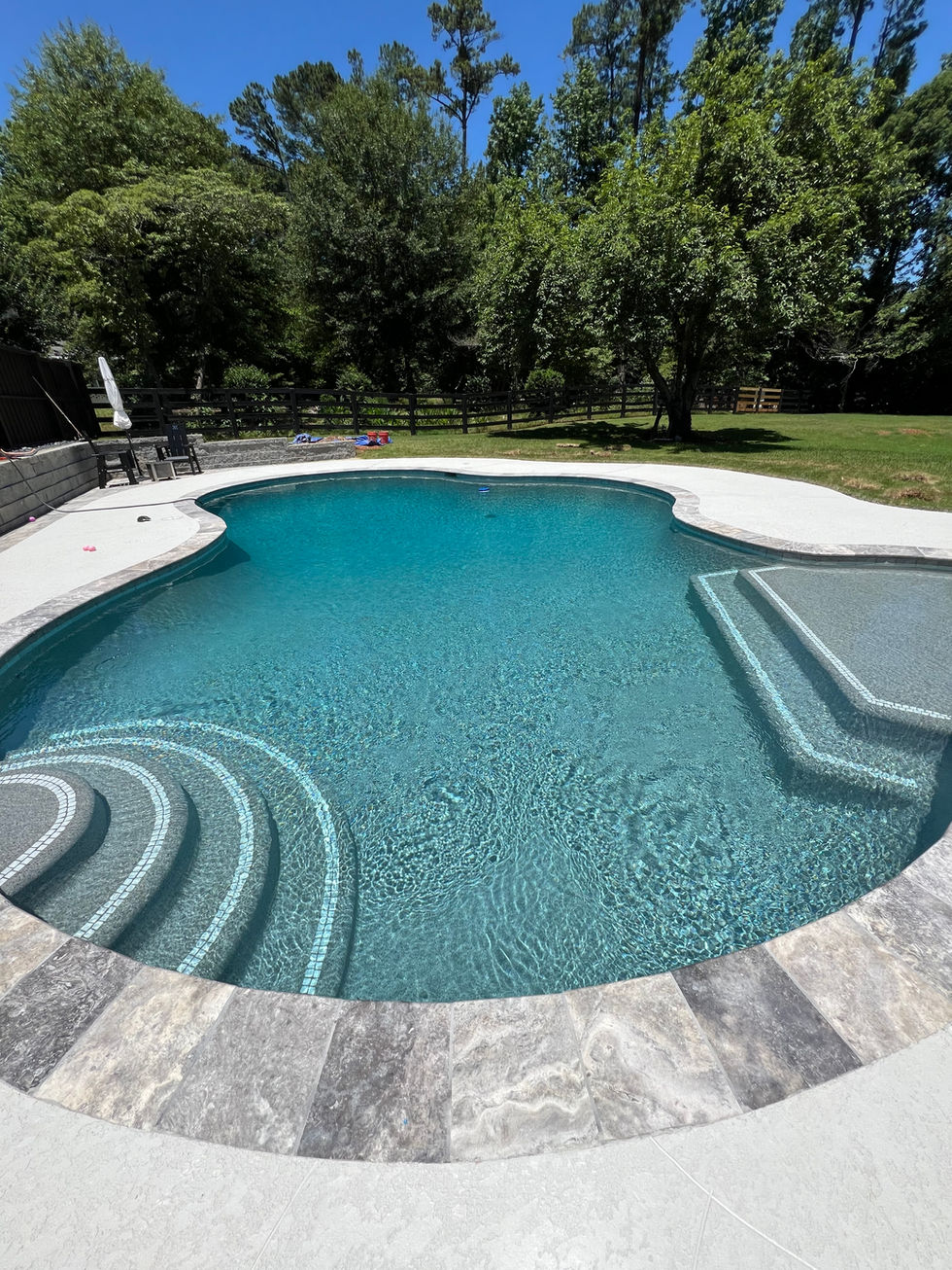 a large swimming pool with stairs and a fence in the background