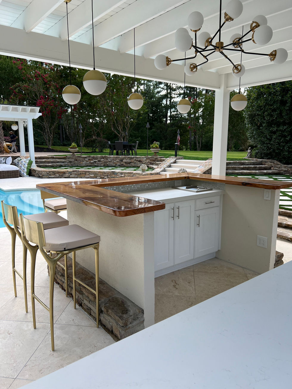 a patio with a bar and stools and a swimming pool