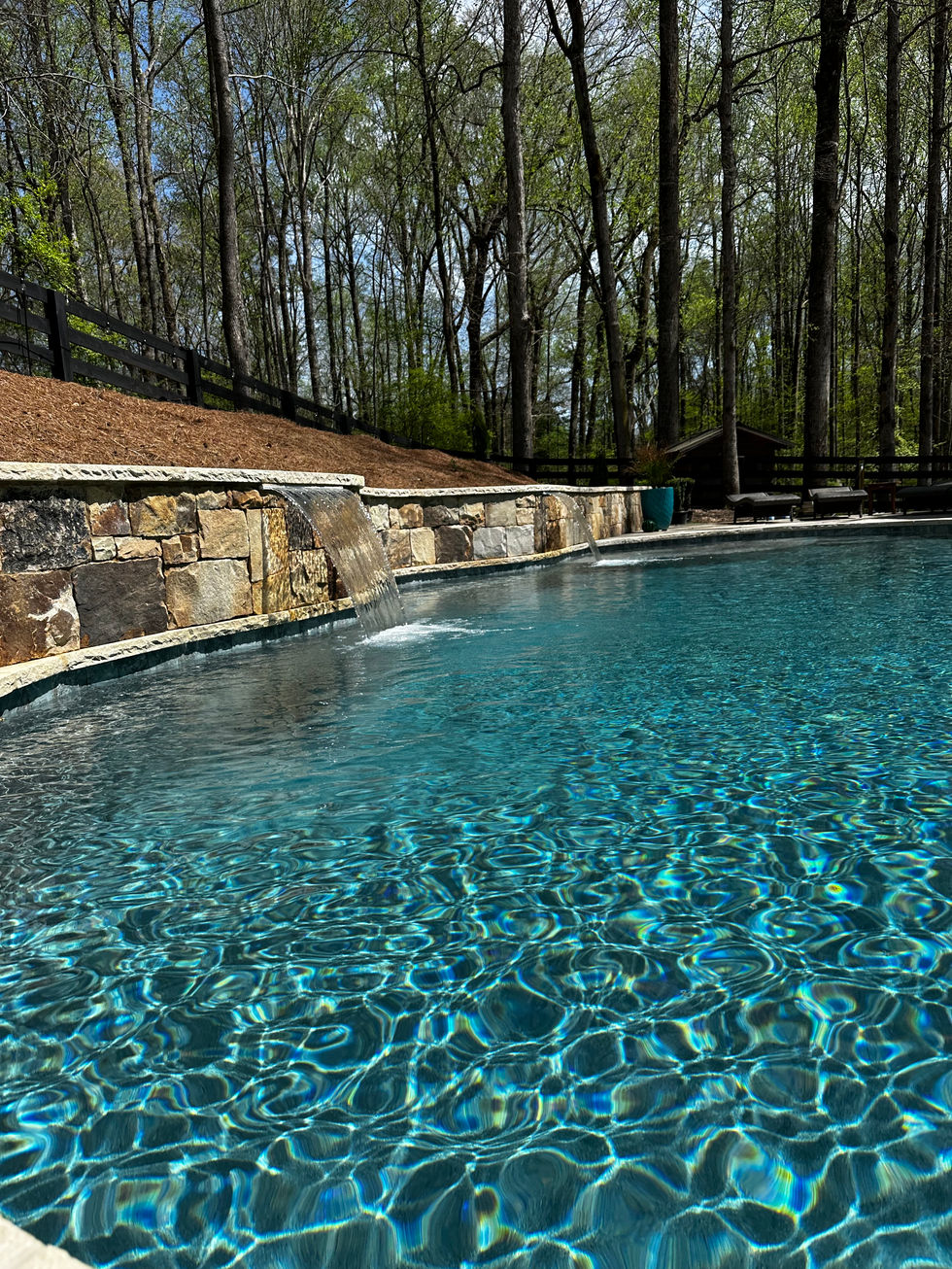 a swimming pool with a waterfall and a stone wall