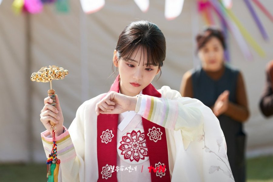 Korean actress Cho Yi-hyun dressed as a shaman, holding ritual bells in a traditional ceremony scene from Head Over Heels