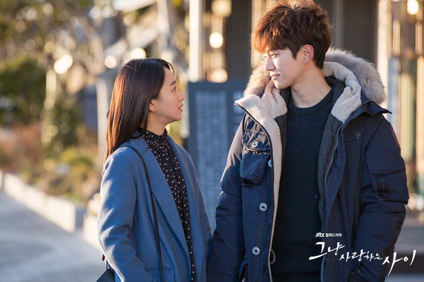 The main couple from Just Between Lovers sharing a tender gaze while walking outside.